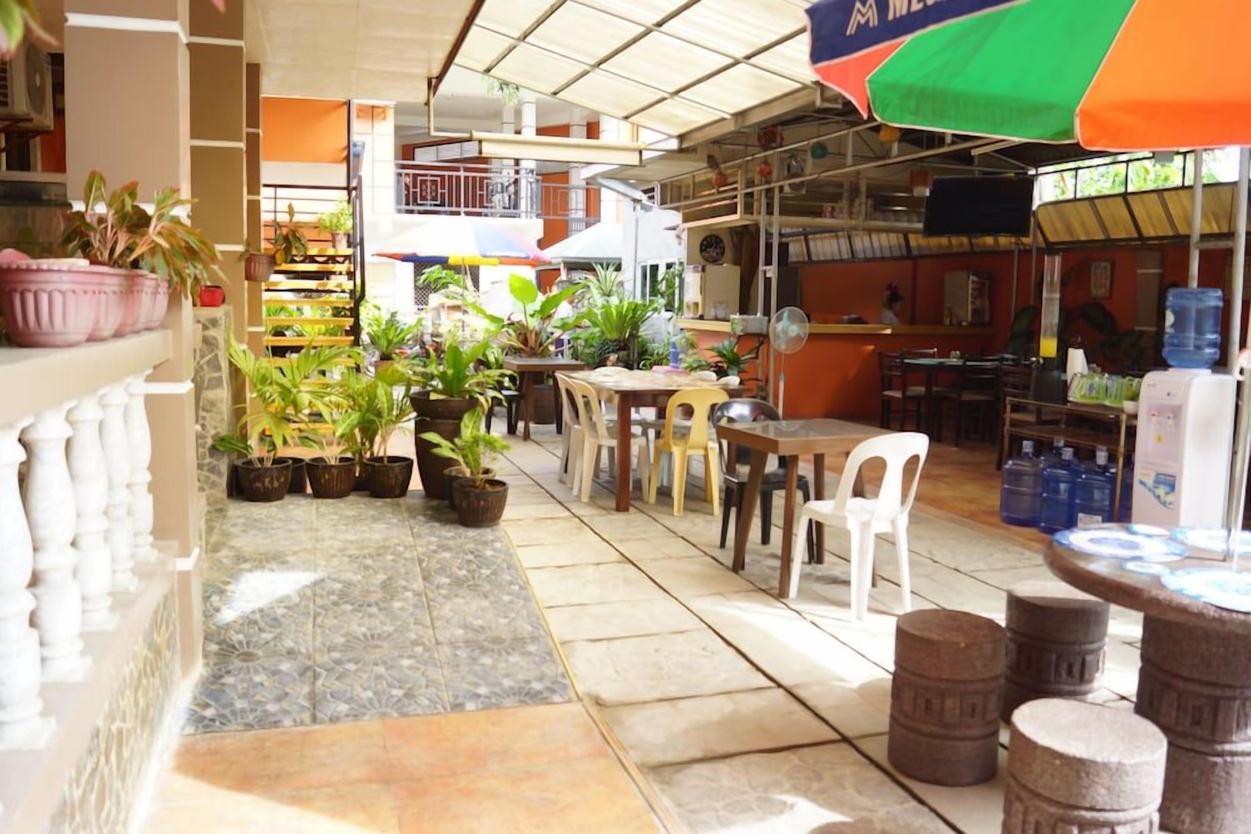 Un espace de restauration intérieur avec des tables et des chaises, des plantes en pot et un distributeur d’eau.