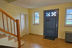 A hallway with a wooden staircase, a blue door with a window, and a small table. - Holiday home with 1 bedroom (Ostseebad Prerow)