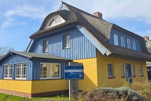 Ein zweistöckiges Gebäude mit blauer Fassade und einem Strohdach.