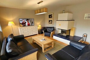 Ein Wohnzimmer mit einer Couch, einem Couchtisch, einem Kamin und einem Fernseher.