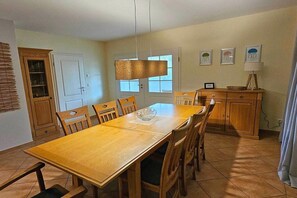 Ein Essbereich mit Holztisch und -stühlen, einer Pendelleuchte und einem Schrank mit einer Schüssel darauf.