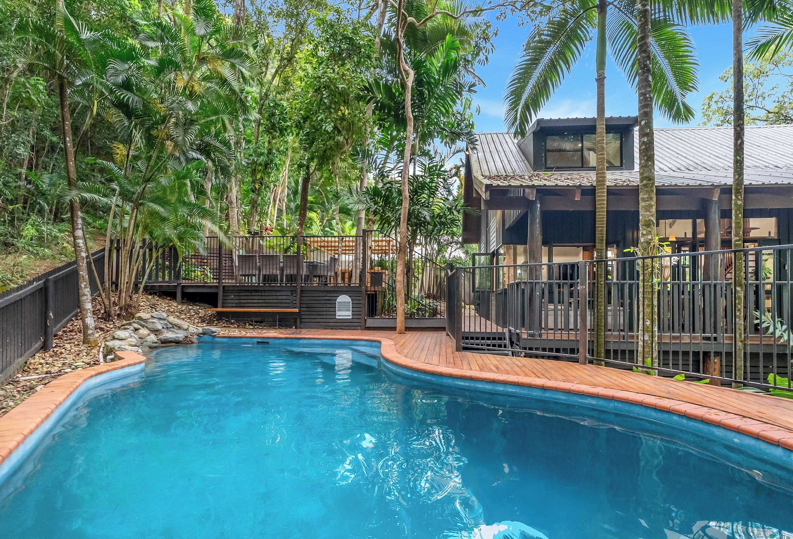 A swimming pool surrounded by lush greenery and a wooden deck.