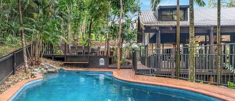 A swimming pool surrounded by lush greenery and a wooden deck.