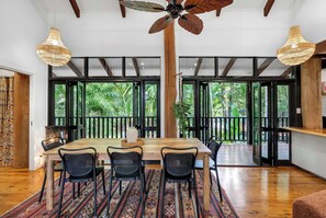 A dining area with a wooden table, black chairs, and a patterned rug. - Treehouse—Serene Tropical Hideaway & Private Pool (Smithfield)