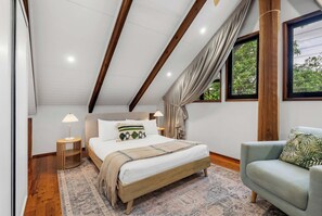 A bedroom with a bed, a chair, a nightstand, and a window with curtains. - Treehouse—Serene Tropical Hideaway & Private Pool (Smithfield)