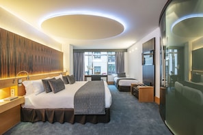 Una habitación de hotel moderna con una cama grande, un escritorio y vistas a la ciudad.