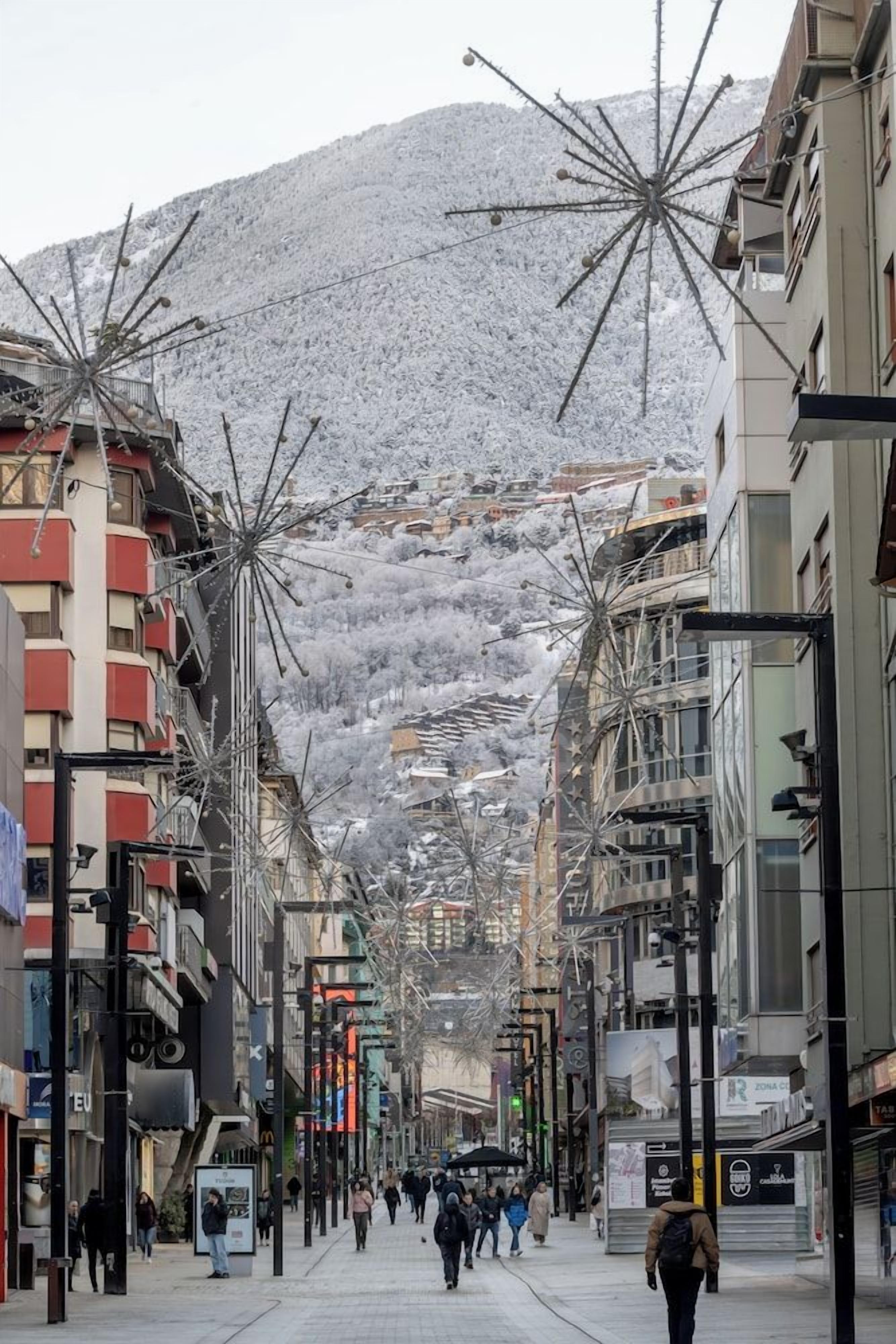 Una calle nevada con edificios y una montaña al fondo.