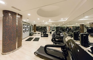 Un gimnasio con cintas de correr, bicicletas estáticas y pesas libres.