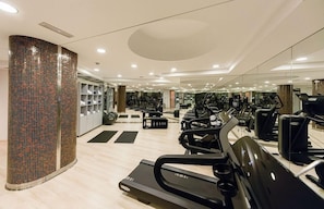 Un gimnasio con cintas de correr, bicicletas estáticas y pesas libres.