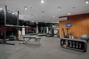 Un gimnasio con equipos de ejercicio variados, incluyendo cintas de correr, máquinas de pesas y pesas libres.