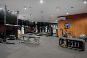 Un gimnasio con equipos de ejercicio variados, incluyendo cintas de correr, máquinas de pesas y pesas libres.