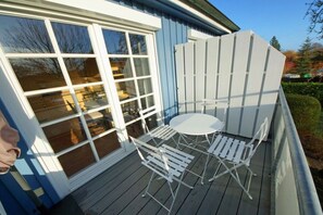 A deck with a table and chairs, a white fence, and a window. - Holiday apartment with 2 bedrooms (Prerow)