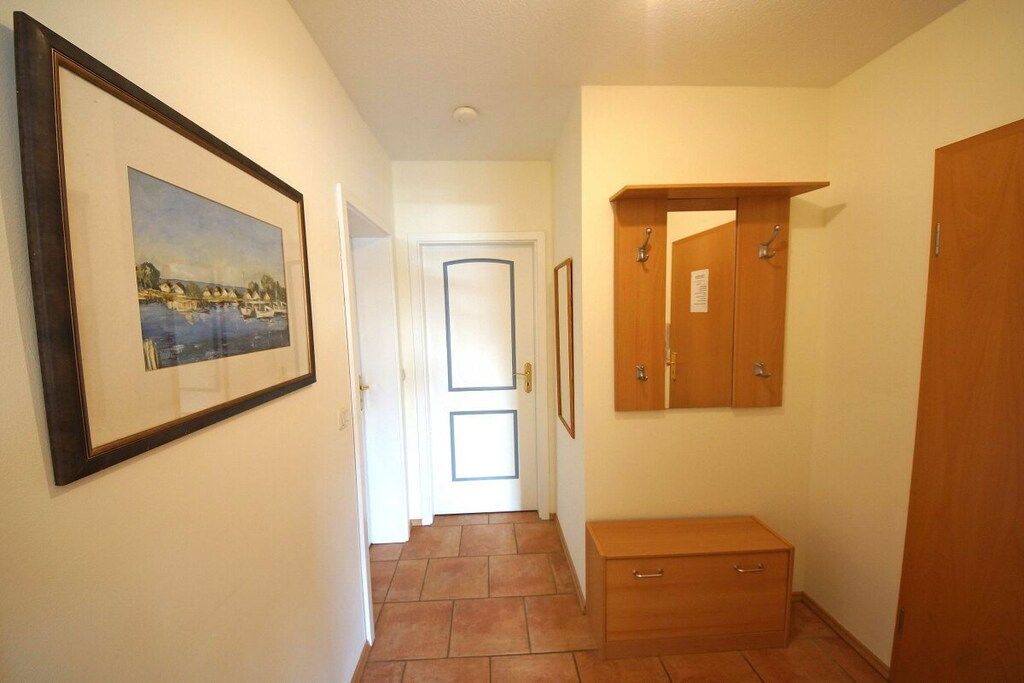 Ein Flur mit einem gerahmten Bild an der Wand, einem Holzschrank und einer Tür am Ende.
