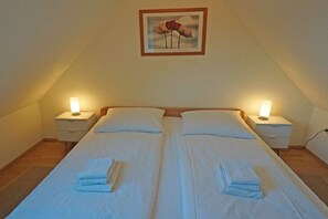 A twin bed with white linens and two bedside tables with lamps. - Holiday apartment with 2 bedrooms (Prerow)