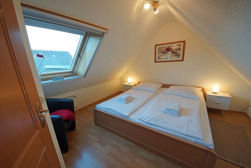 Une chambre à coucher avec un lit, des tables de chevet, une fenêtre et un tableau au mur.