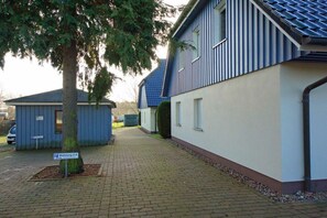 A residential building with a paved driveway, a tree, and a small shed. - Holiday apartment with 2 bedrooms (Prerow)