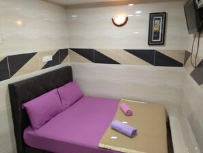 A room with a bed, a wall-mounted TV, and a light fixture.