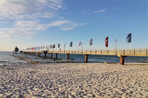 A beach with a pier extending into the water, featuring multiple flags. - Holiday apartment near the spa park (Ostseeheilbad Zingst)