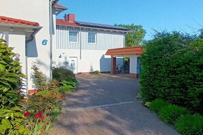A building with a number 6 on the side, a paved driveway, and a small covered area with a bicycle. - Holiday apartment near the spa park (Ostseeheilbad Zingst)