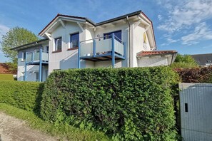 Ein zweigeschossiges Haus mit einem Balkon im oberen Stockwerk.
