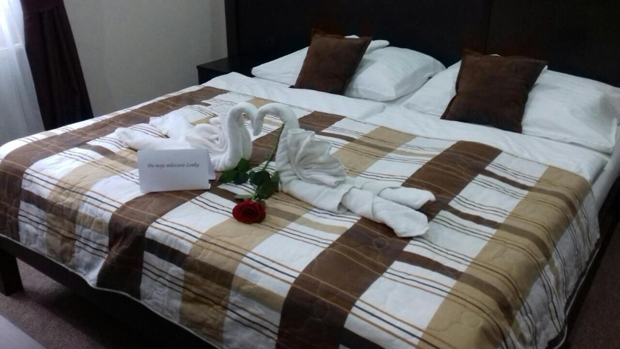 A neatly made bed with a checkered bedspread, two brown pillows, and a bouquet of white flowers.