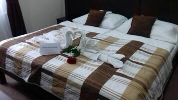 A neatly made bed with a checkered bedspread, two brown pillows, and a bouquet of white flowers.