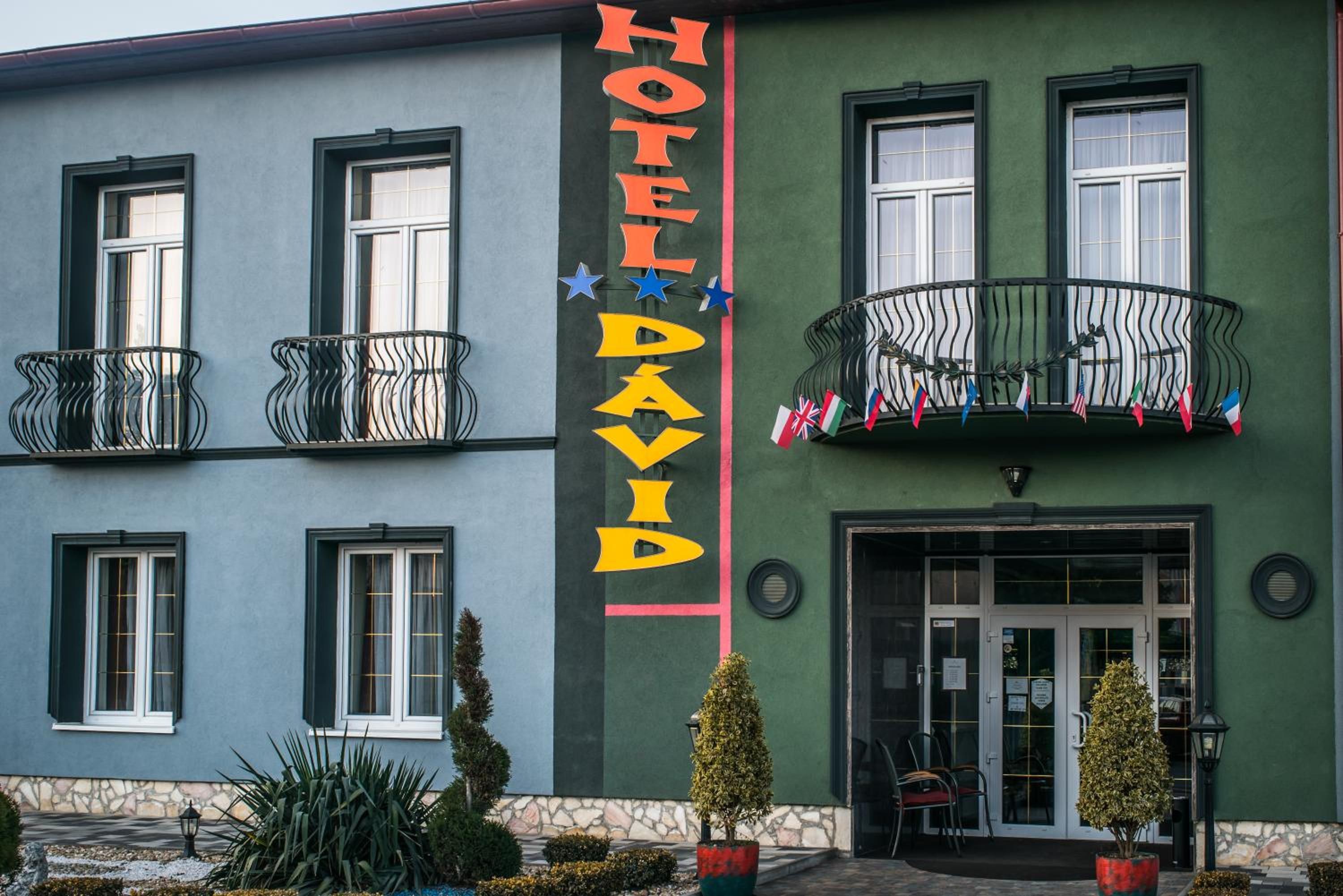 A hotel with a prominent sign, balconies with railings, and a door entrance.