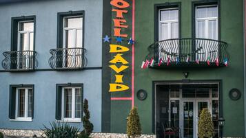 A hotel with a prominent sign, balconies with railings, and a door entrance.