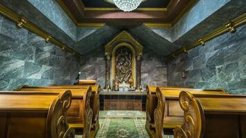 An interior with pews, a central altar, and a chandelier.