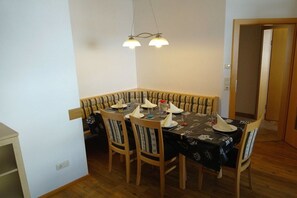 Ein Essbereich mit einem Ecktisch, Stühlen und einer Pendelleuchte.