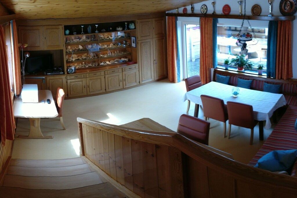 A wooden interior with a dining area, a television, and a shelf with decorative items.