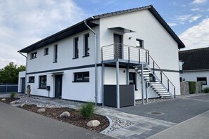 A modern two-story building with a balcony, a staircase, and a well-maintained garden area. - Holiday apartment with 3 bedrooms (Zinnowitz)