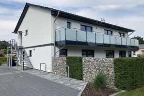 Een modern, tweelaags gebouw met een balkon, een trap en een stenen muur.