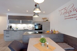 A modern kitchen with a dining area, a built-in oven, and a wall-mounted light fixture. - Holiday apartment with 3 bedrooms (Zinnowitz)