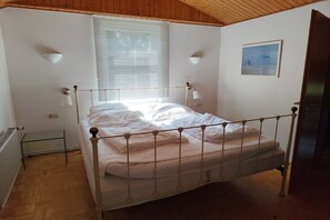 A bedroom with a bed, a radiator, a window with blinds, and a door. - Holiday apartment with 3 bedrooms (Ostseebad Dierhagen)