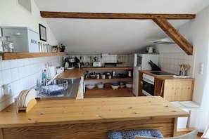 Une cuisine compacte dotée de plans de travail en bois, d’un four encastré et d’une variété d’ustensiles et d’appareils de cuisine.