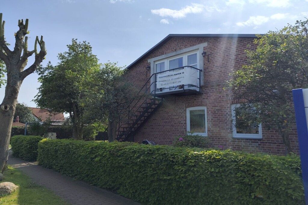 A brick building with a sign indicating it is a hotel. There is a pathway leading to the building, and a tree is visible to the left.