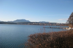 Ein See mit einer Anlegestelle und Booten, umgeben von Bergen und Häusern.