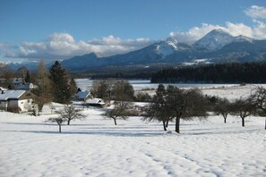 Un paysage enneigé avec des maisons et une chaîne de montagnes en arrière-plan.