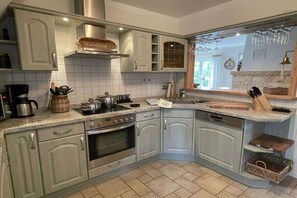 A kitchen with white cabinets, a stove, oven, and a dishwasher. There is a window with a view of the outside. - Holiday home with 2 bedrooms (Seebad Karlshagen)