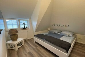 Una camera da letto con un letto, un tavolino con una lampada, una finestra con persiane e una decorazione a muro.