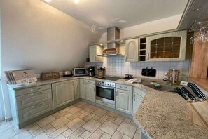 Una cucina con forno, microonde e cappa aspirante.
