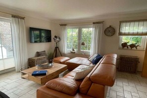 Un salon avec un canapé en cuir, une table basse en bois et un téléviseur fixé au mur.