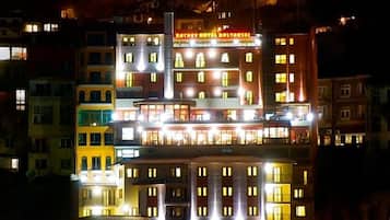 Un hotel de varios pisos con ventanas e balcones iluminados, que destaca un cartel en la parte superior.