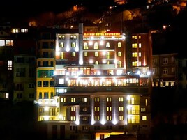 A multi-story hotel with illuminated windows and balconies, featuring a prominent sign at the top.