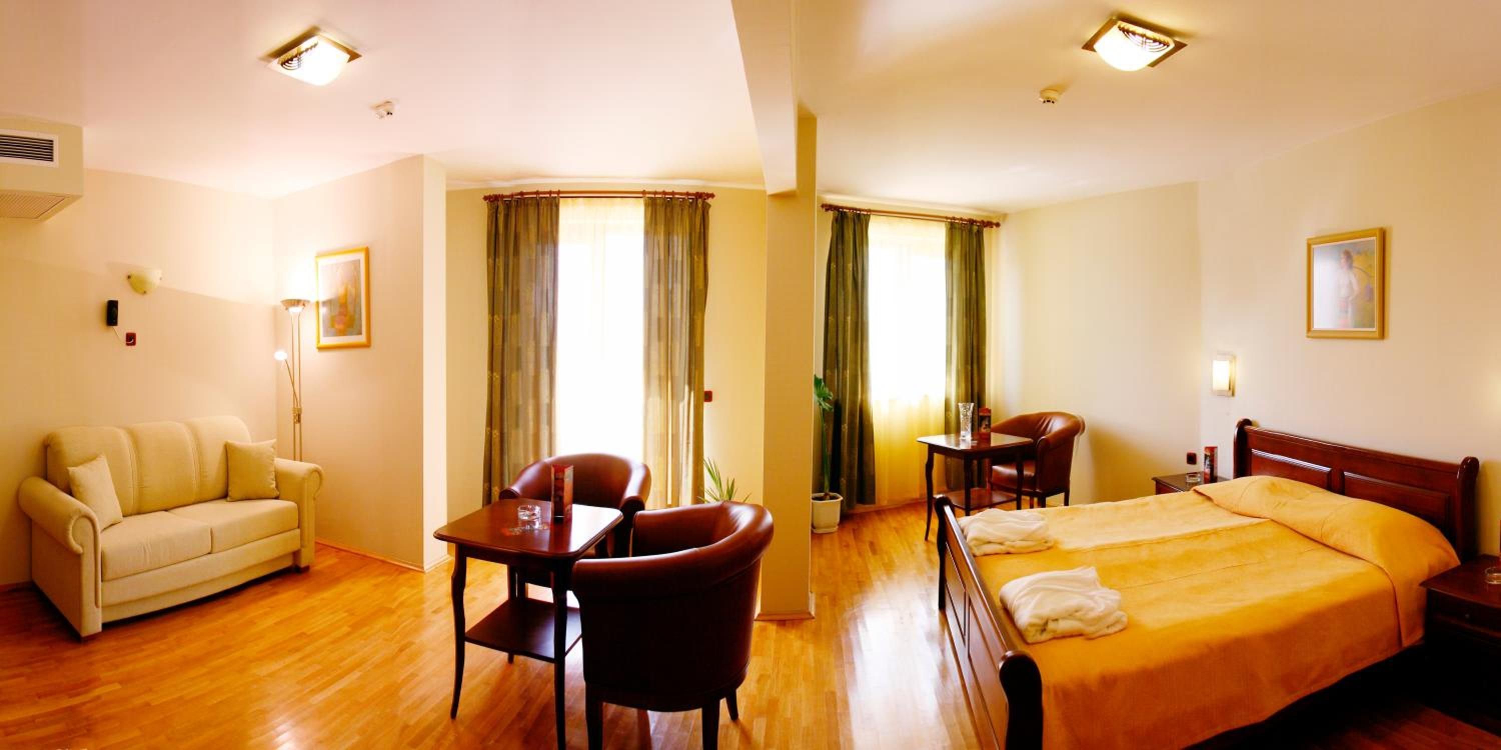 Una habitación de hotel con una cama, un sofá, una mesa de comedor y sillas.