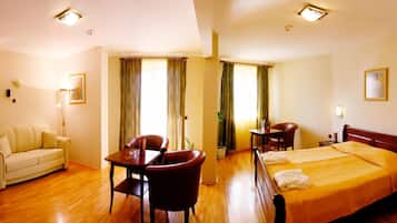 Una habitación de hotel con una cama, un sofá, una mesa de comedor y sillas.