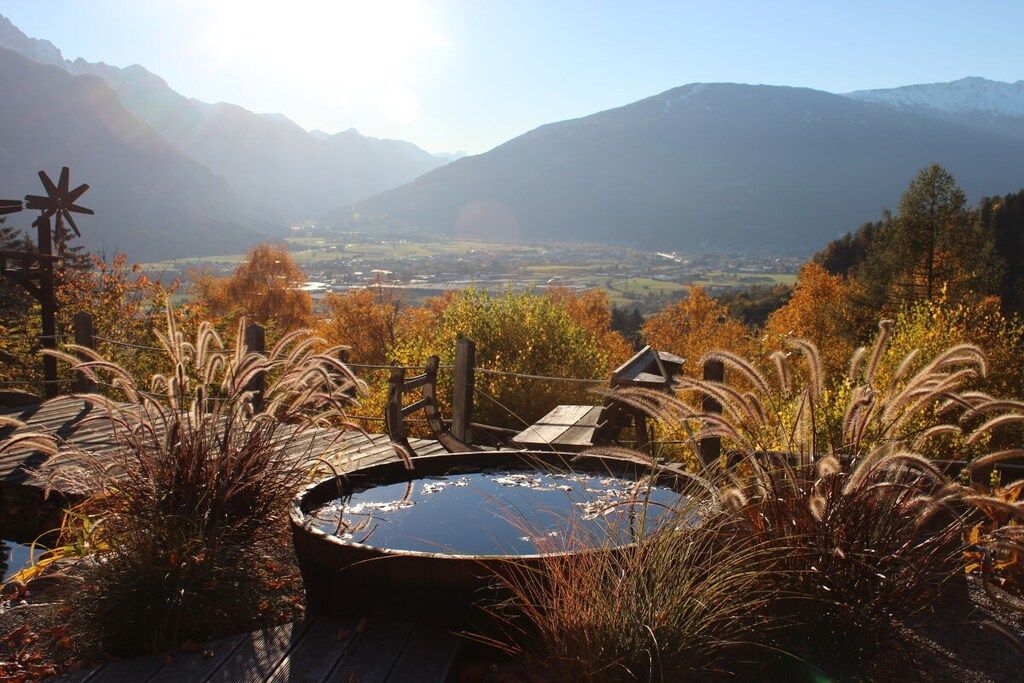 A hot tub surrounded by autumn foliage with a mountainous backdrop.