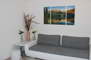 A modern living room with a grey sofa, a small white table, and two vases with flowers. - Panoramic view - East Tyrol (9991 Dölsach)