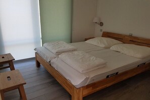 A single-bed room with a wooden frame, a bedside table, a lamp, and a window with a view. - Holiday home with 1 bedroom (Wendisch-Langendorf)